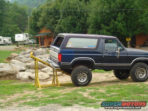Dark blue SUV on a yellow ramp, with off-road tires and a purple top