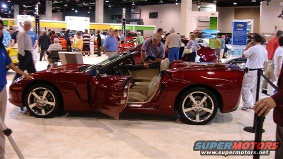 Red convertible sports car with doors open at an auto show