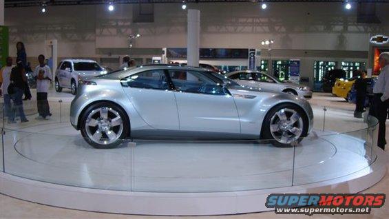 Silver concept car with unique wheels on a display turntable at an auto show