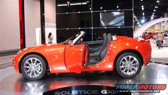 Orange Pontiac Solstice GXP convertible with doors open, chrome wheels, on display