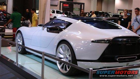 White concept car with unique wheel design and black accents, displayed indoors