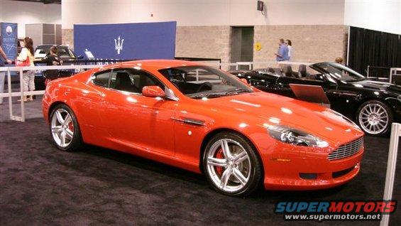 Orange coupe with silver wheels and a black convertible behind it