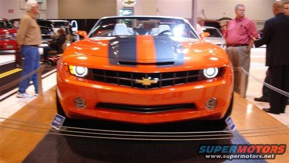Front view of an orange convertible Camaro with a dark stripe on the hood