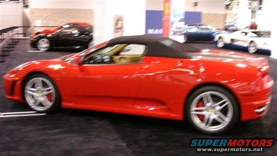 Red convertible sports car with black top, other cars in background