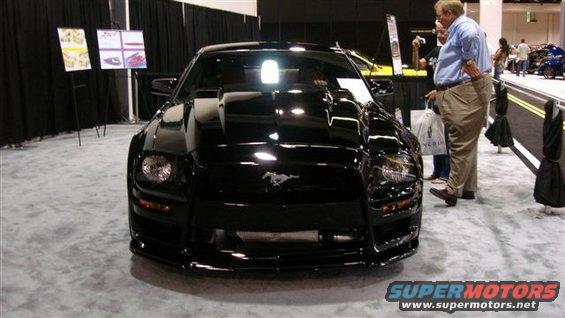 Black Ford Mustang with a prominent hood scoop and a horse emblem on the grille, viewed from the front