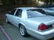 1999 Ford Crown Victoria - A silver sedan is parked in a lot next to another vehicle, viewed from the rear three-quarter angle.