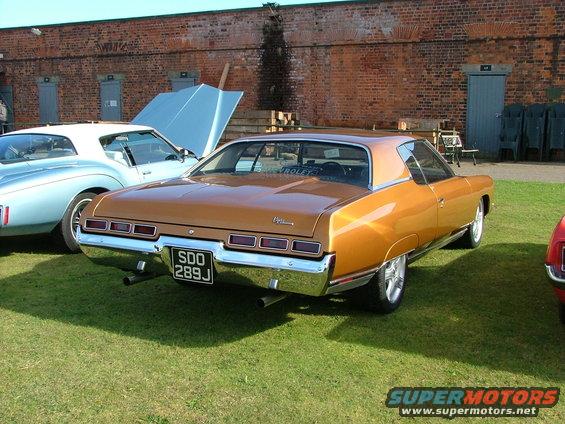 1971 Chevrolet Caprice coupe, rear view, parked on grass. Another car is visible to the left