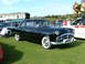 1988 Ford Sport - A classic black Packard sedan is displayed on a grassy field, with a train and other vehicles in the background.