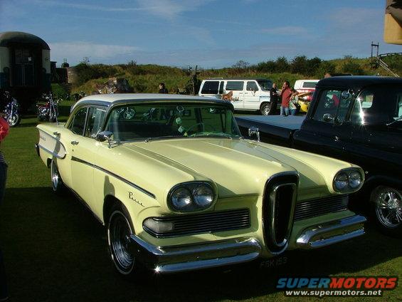 Yellow 1958 Edsel Pacer sedan with a white roof, parked next to a black pickup truck