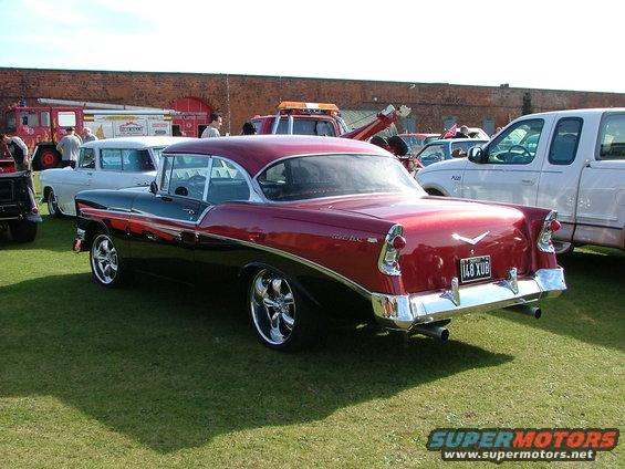 Two-tone red and black 1956 Chevrolet Bel Air coupe, rear view. Other cars and fire trucks in background