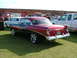 1988 Ford Sport - A classic two-tone Chevrolet coupe is parked on the grass with other vehicles and buildings in the background.