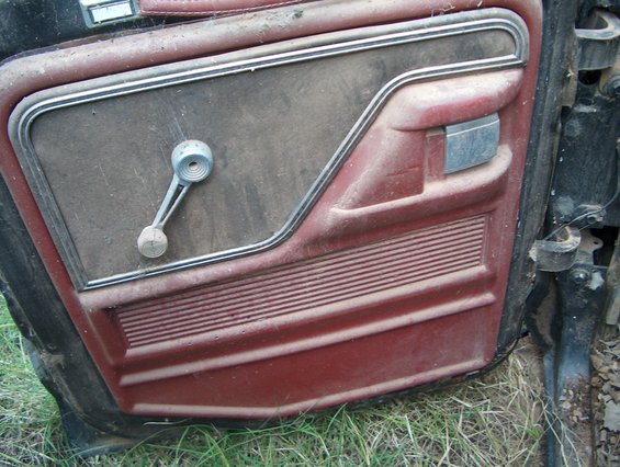 1979 Ford Bronco interior door panel with red trim and chrome window crank