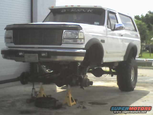 White 1995 Ford Bronco with front end raised on jack stands, undergoing maintenance