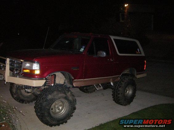 Red SUV with large tires and lifted suspension parked at night