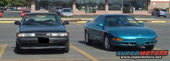 Black sedan and a teal coupe parked in a lot. Text on the teal car reads SUPERMOTORS