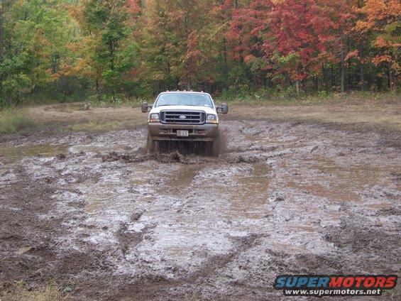 White Ford F-250 Super Duty driving through mud puddle, front view. Year 2004