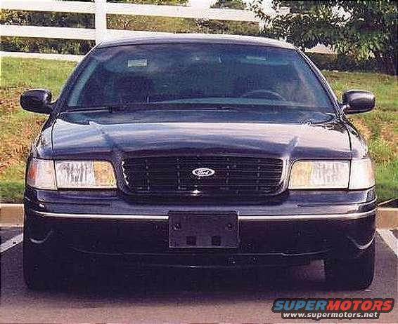 Dark blue Ford Crown Victoria front view, parked, with a white fence in the background