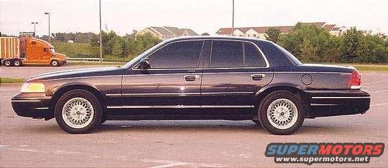 Side view of a dark blue Ford Crown Victoria sedan parked on asphalt