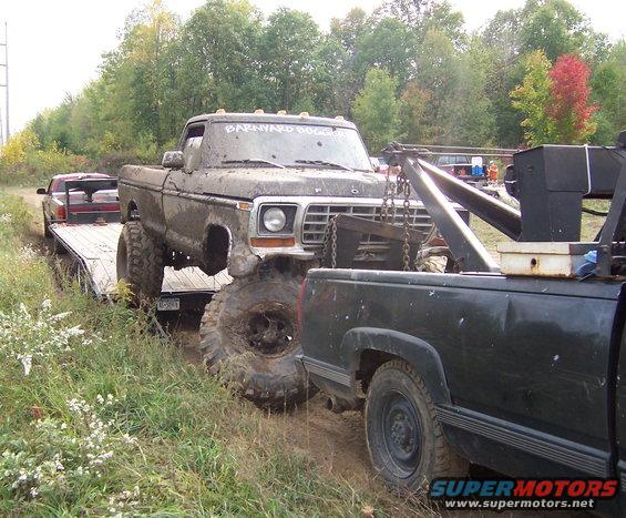 Muddy 1978 Ford F-Series pickup truck on a tow truck bed, front view