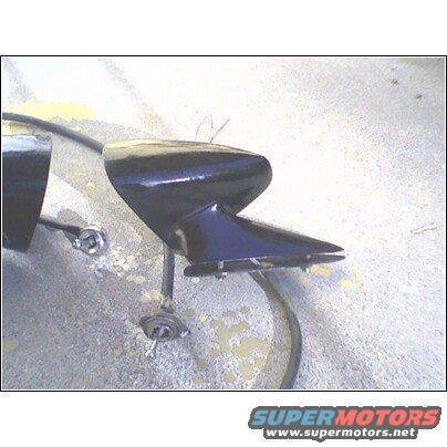 Two black car fender trim pieces, one with a pointed aerodynamic shape, resting on a concrete surface