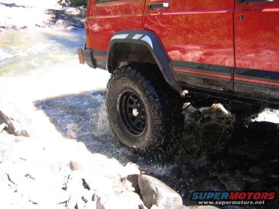 Red 1996 Jeep Cherokee side view driving through water
