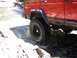 1996 Jeep Cherokee - A red 1996 Jeep Cherokee navigates a rocky stream, kicking up water as it goes.