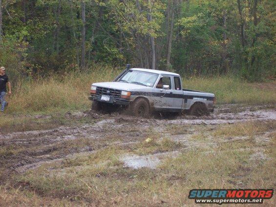 1990 Ford Ranger stuck in deep mud with trees in background