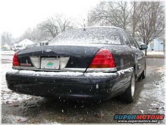 Dark sedan, rear view, covered in snow, with a license plate