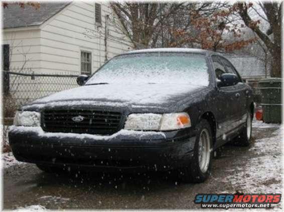 Front 3/4 view of a black 1999 Ford Crown Victoria covered in snow