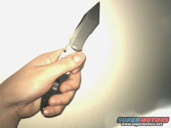 Hand holding a folding knife with a sharp, angular blade