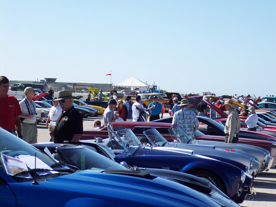 People milling around a car show with many classic cars on display