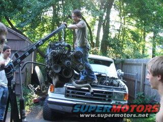 Engine being removed from a white Ford truck's hood