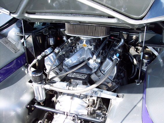 Engine bay with polished chrome V8 engine, air filter, and braided hoses. Silver and purple exterior visible