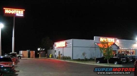 Cars parked at night in front of a Hooters restaurant