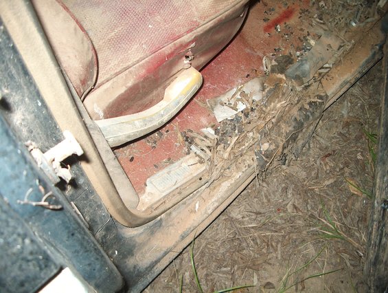 Car interior door sill with red upholstery and debris