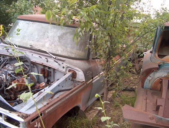 Rusted pickup truck with open hood and engine exposed, parked next to another vehicle