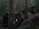 1989 Ford Bronco - A black 1989 Ford Bronco navigates a wooded trail, with a red SUV following behind.