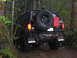 1989 Ford Bronco - Black 1989 Ford Bronco on a wooded trail, equipped for off-roading with a spare tire and gas can.