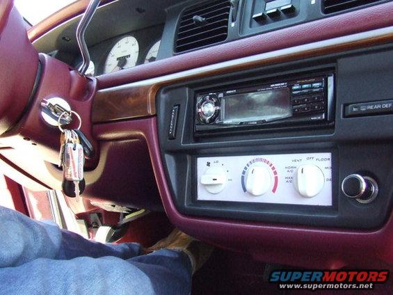 Maroon dashboard interior of a 1992 Ford Crown Victoria showing white face gauges, radio, and climate controls