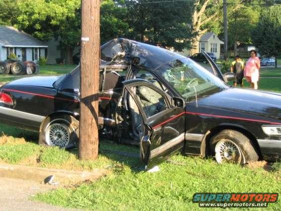 Black sedan crashed into a utility pole, roof crushed, driver's door open