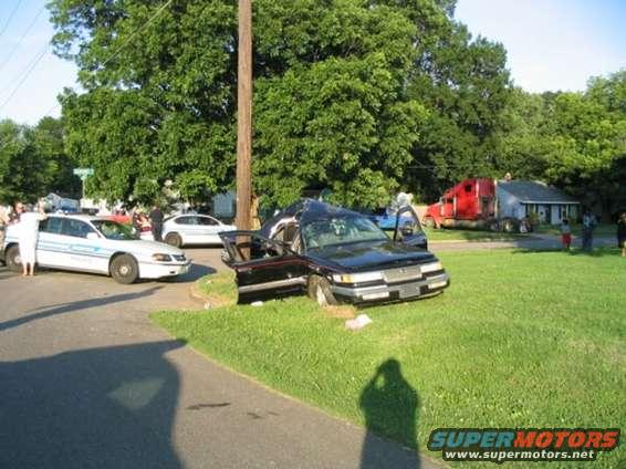 Black sedan with doors open, crashed on grass, front end damaged