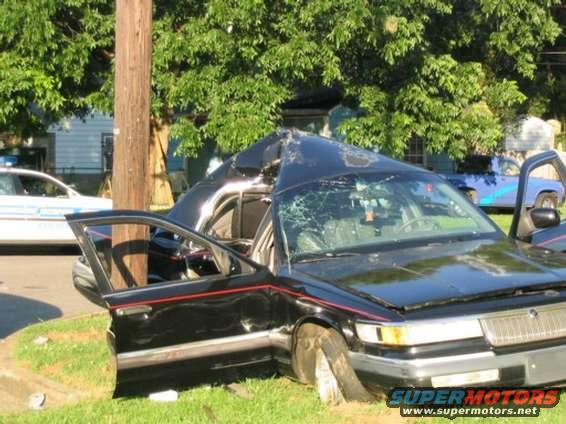Black 1999 Ford Crown Victoria with crushed roof, front 3/4 view