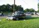 1999 Ford Crown Victoria - A black sedan with its doors open and roof damaged sits on the grass next to a road.