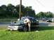 1999 Ford Crown Victoria - A 1999 Ford Crown Victoria is examined by a person in uniform after an apparent incident, with another vehicle visible in the background.