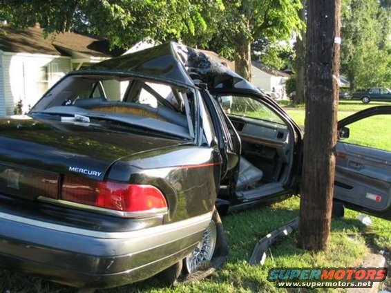 Mercury Grand Marquis with severely damaged roof after hitting a pole. Driver door is open