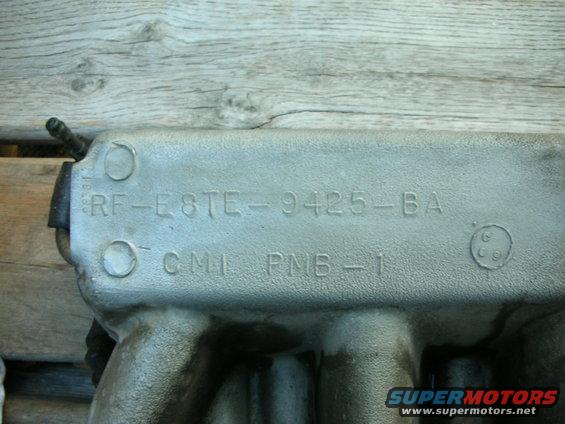 Close-up of an engine intake manifold with part numbers RF-E8TE-9425-BA and CMI PNB-1 stamped on it
