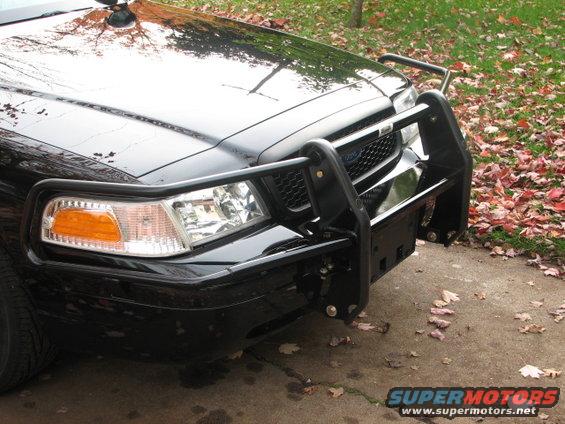 Front view of a black 2000 Ford Crown Victoria with a push bumper and police light on top