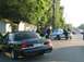 1999 Ford Crown Victoria - A black 1999 Ford Crown Victoria is seen from the rear, parked on a street with other vehicles and people present.