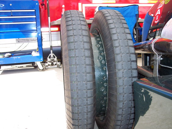 Two tires, one on a rim, next to a blue toolbox and a red background