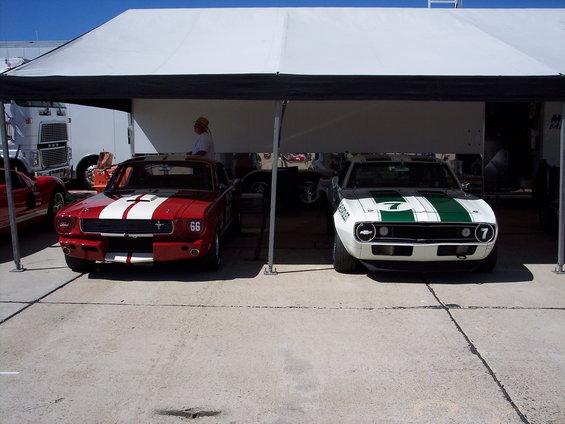 Red and white 1966 Ford Mustang race car with racing stripes and number 66 on the fender